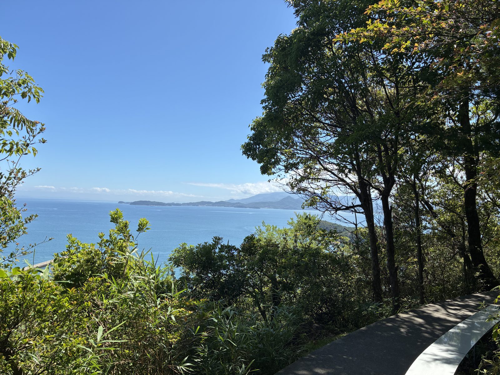 緑豊かな木々の間から瀬戸内海を望む小道